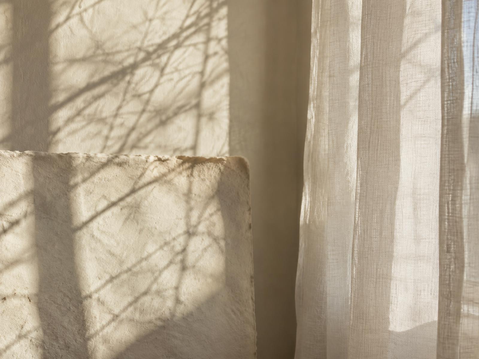 Morning branch shadows across handmade paper and linen